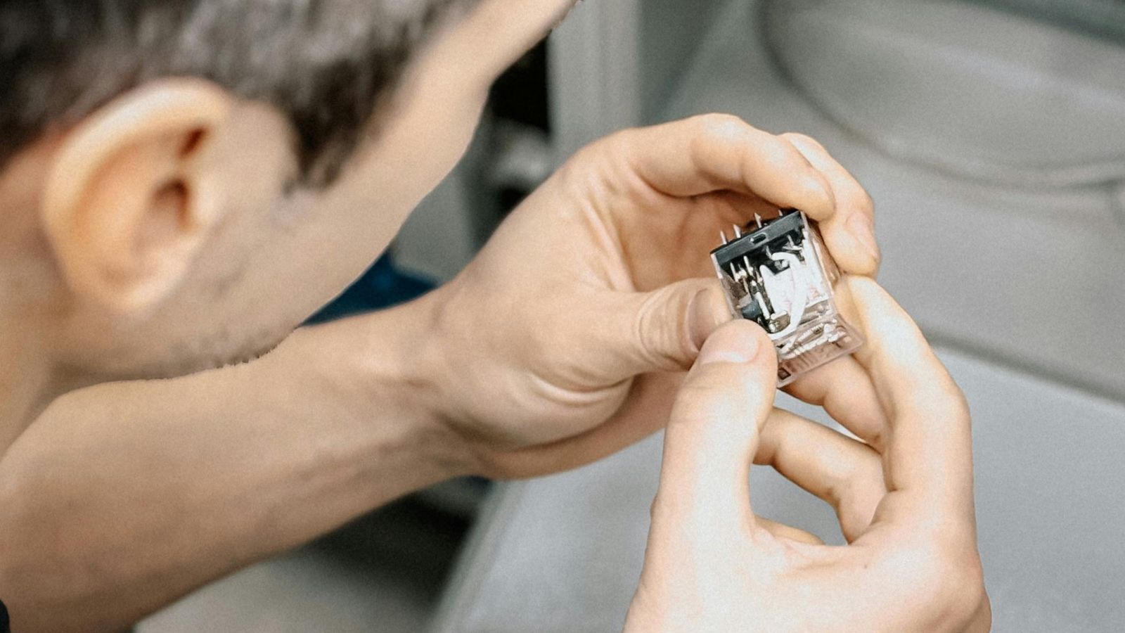 Des mains manipulent un petit connecteur électronique