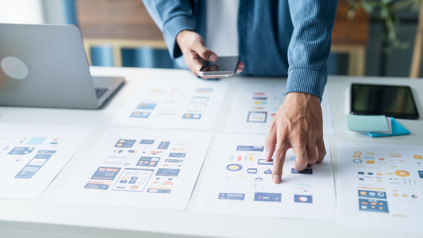 Maquettes d'écrans d'une application mobile posées sur un bureau
