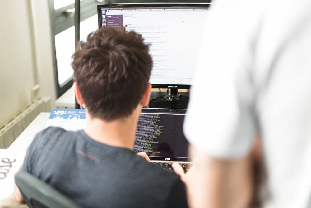 Un développeur Serli au travail devant son écran, un collègue à ses côtés
